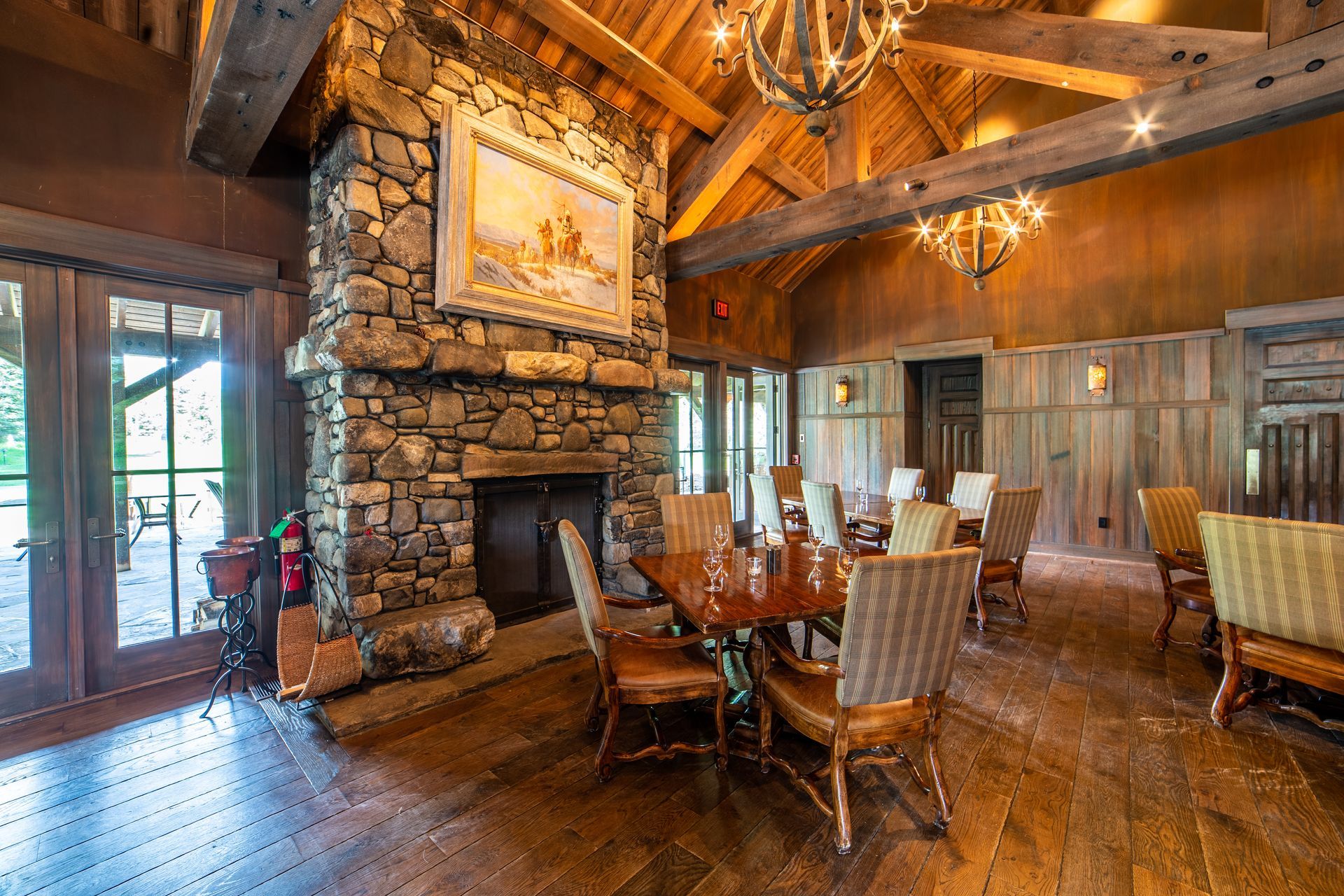 A large dining room with a stone fireplace and tables and chairs.