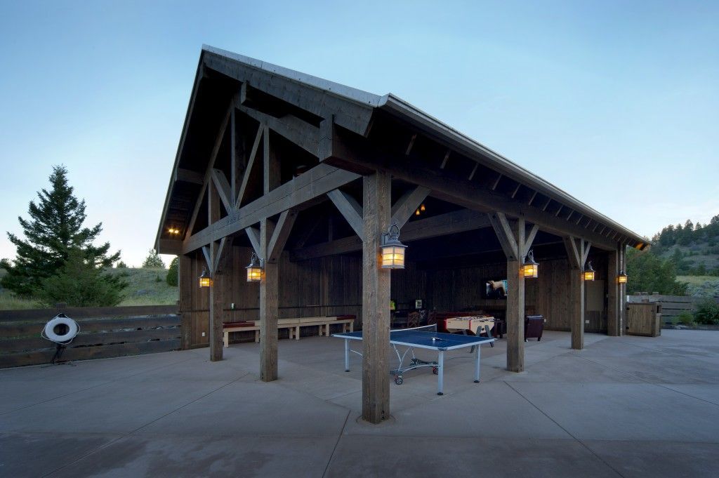 A large wooden building with a ping pong table underneath it.