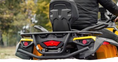 A man is riding a four wheeler with a rear rack.