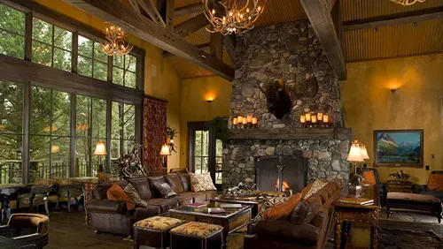 A living room with a large stone fireplace and lots of windows