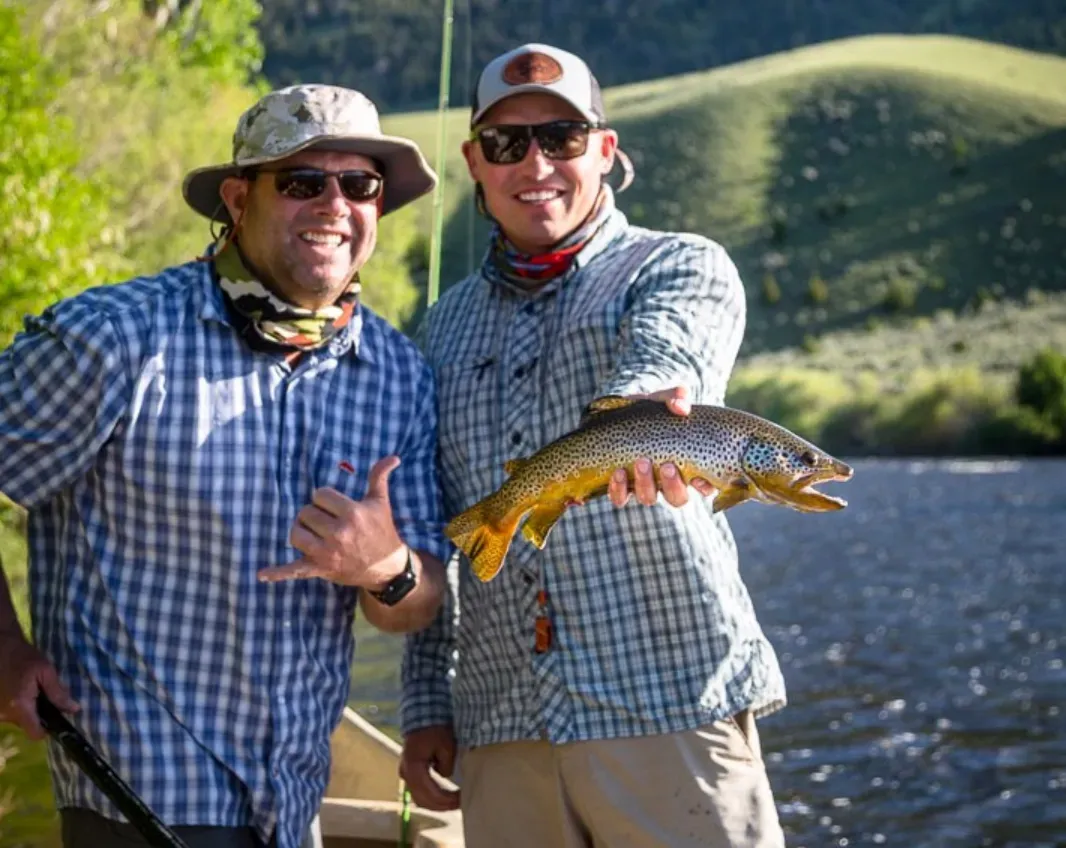 Two men are standing next to each other holding a fish in their hands.