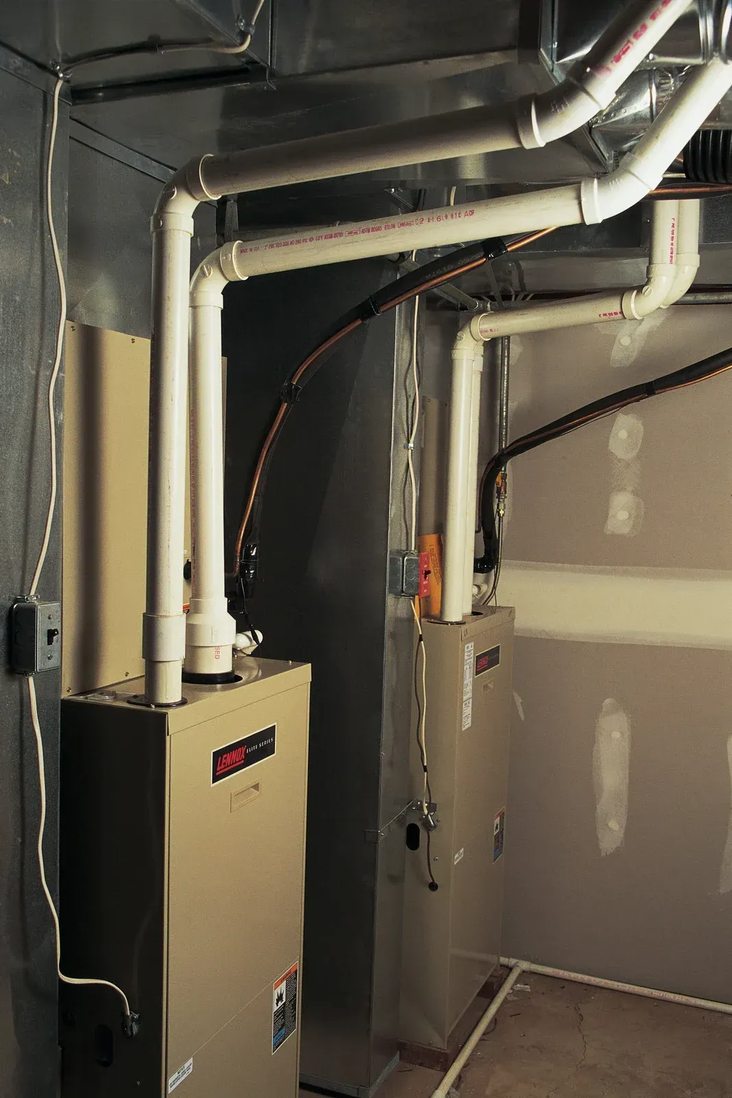A room with a furnace and pipes hanging from the ceiling.