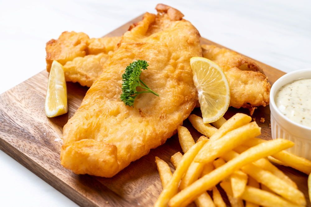 A Wooden Cutting Board Topped With Fish And French Fries — Mulgrave Seafoods In Bungalow, QLD