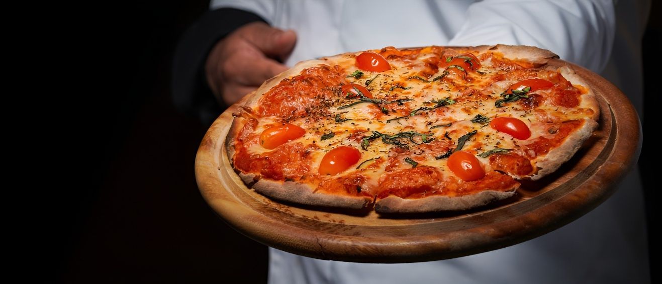 A Man is Holding a Pizza on a Wooden Tray — Mulgrave Seafoods In Bungalow, QLD