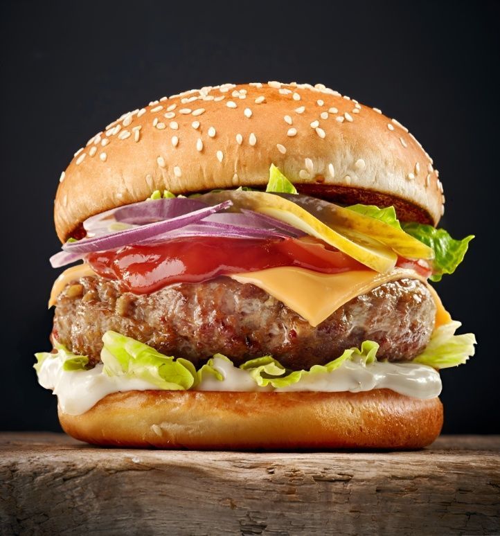 A Hamburger With Cheese, Lettuce, Onions Meat and Tomatoes on a Wooden Cutting Board — Mulgrave Seafoods In Portsmith, QLD