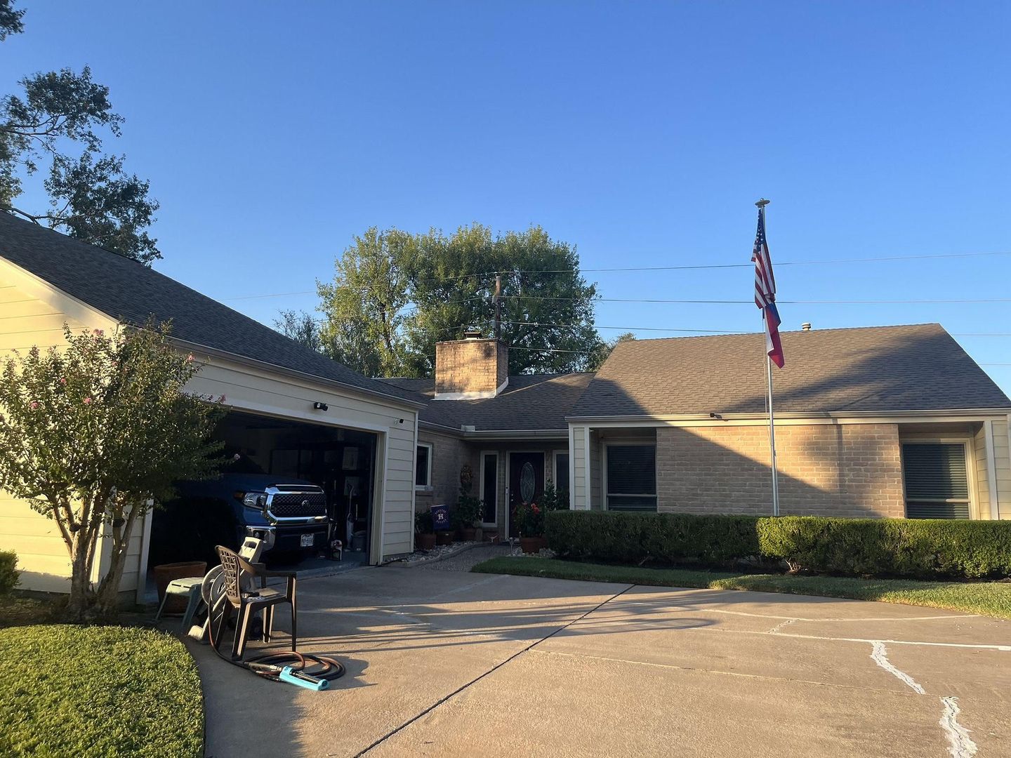 House with attached garage, driveway, and American flag on a sunny day.
