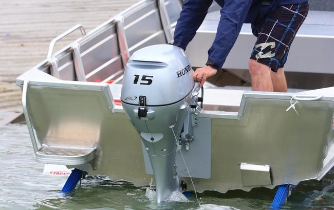 Person Adjusting a Silver 15-horsepower Outboard Motor — TJM Rockhampton in Rockhampton City, QLD