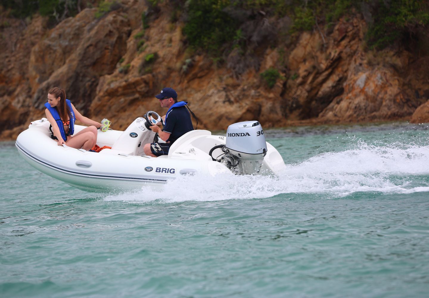 a White Motorboat With Two People, Cruising on the Water Near a Rocky Shore — TJM Rockhampton in Rockhampton City, QLD
