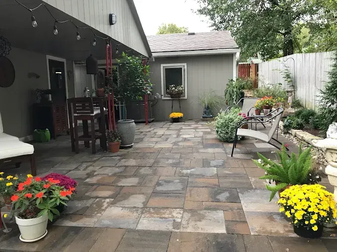 A patio with flowers and chairs in front of a house.