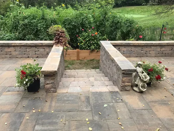 A patio with stairs leading up to a garden.