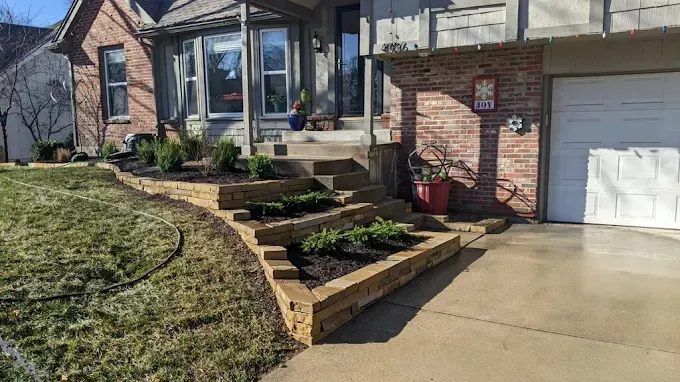A brick house with a white garage door and a stone wall in front of it.