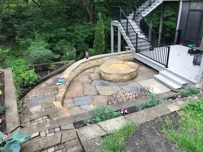 A fire pit on a patio next to a house with stairs.