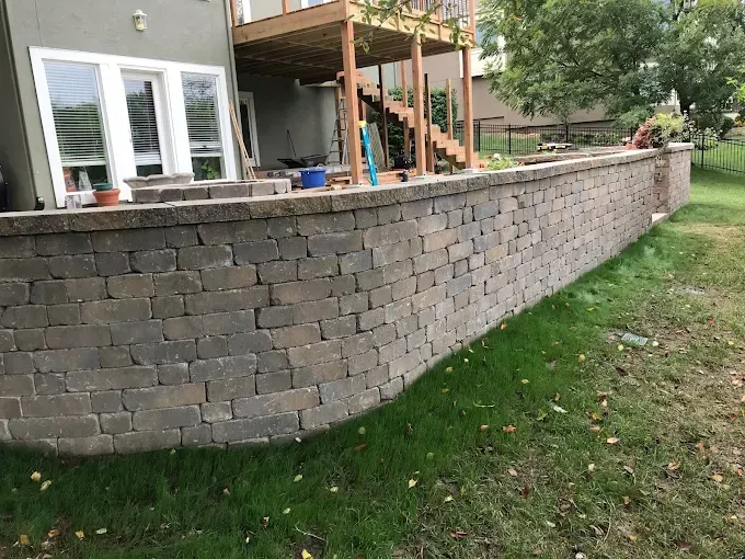 There is a large brick wall in the backyard of a house.