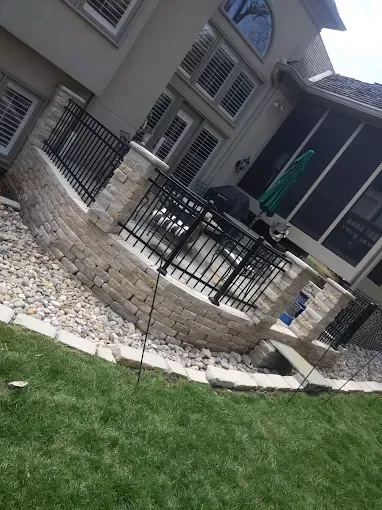 A large house with a patio and a fence in front of it.