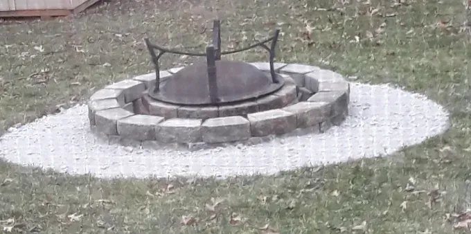 A fire pit is sitting in the middle of a lush green field.