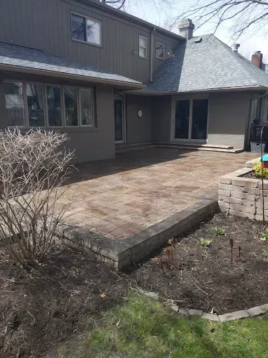 A backyard with a patio and a house in the background.