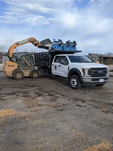 A dump truck is being towed by a bulldozer in a parking lot.