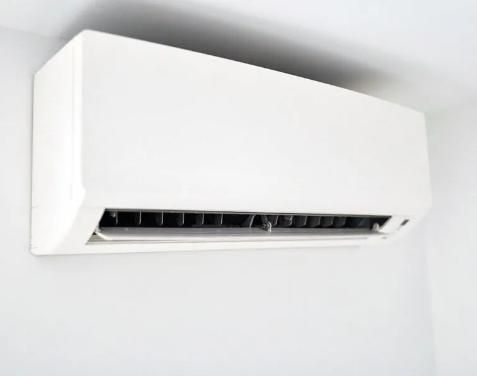 A White Air Conditioner is Hanging on a White Wall — Sparky Mid North Coast In Forster, NSW