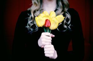 Person holding yellow tuplips with one single red tulip