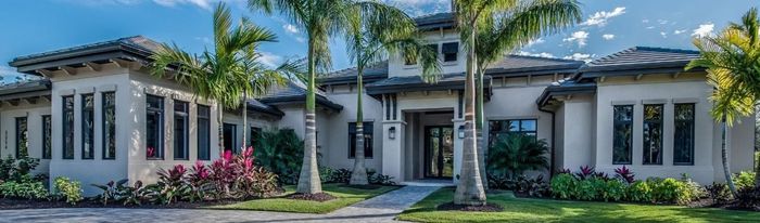 A large house with a lot of windows and palm trees in front of it.