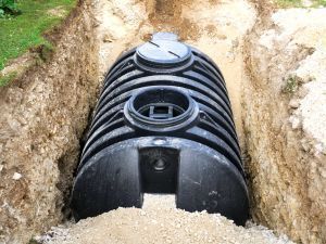 A large black septic tank is sitting in a trench.