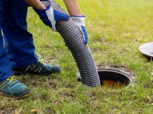 A person is pumping a hose into a septic tank.