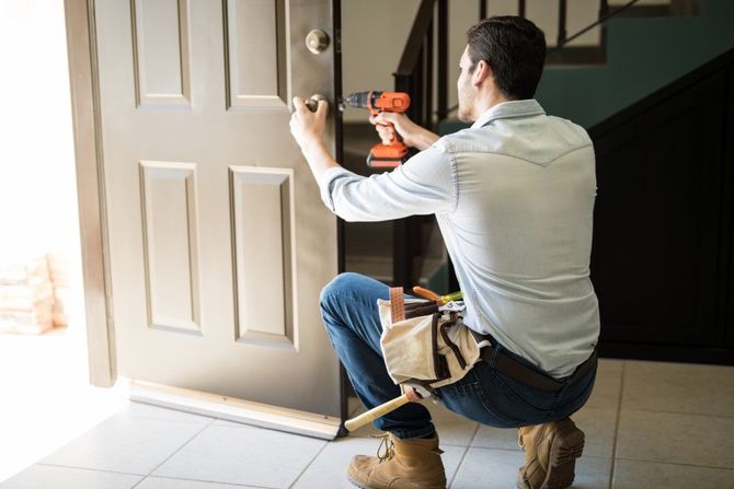 Worker installing a door with a drill in a bright entryway