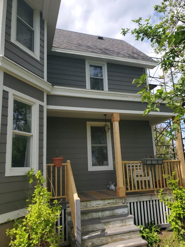 Two-story house with gray siding, white trim, and a wooden porch.