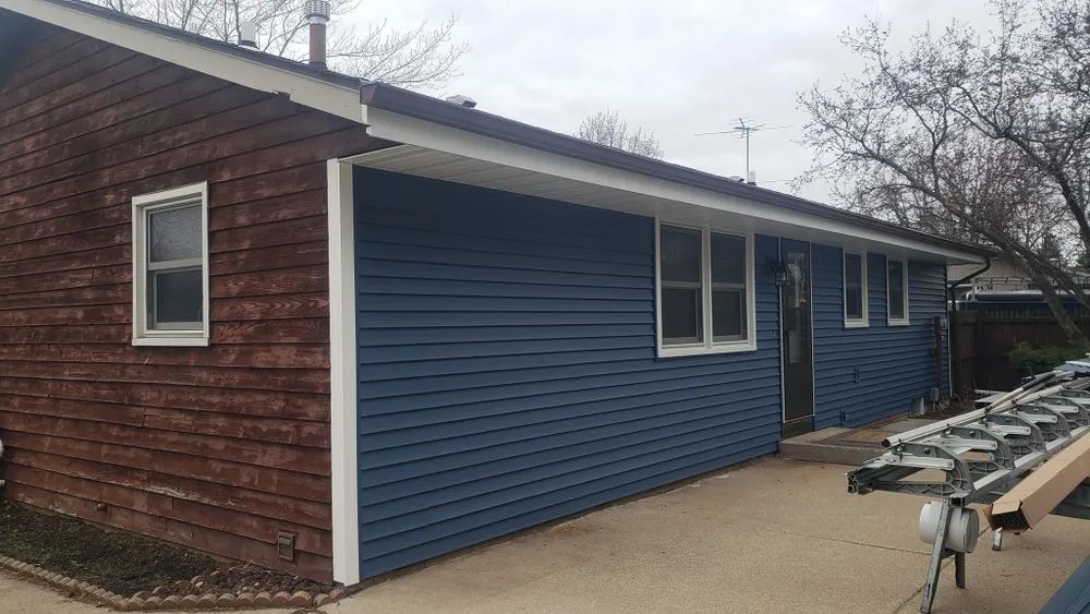 Blue siding and white trim on a house with brown siding and windows.