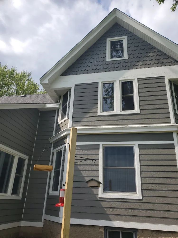 Gray house with white trim, horizontal siding, and multiple windows.