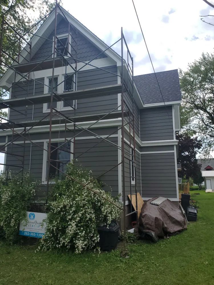 House exterior with new gray siding; scaffolding present.
