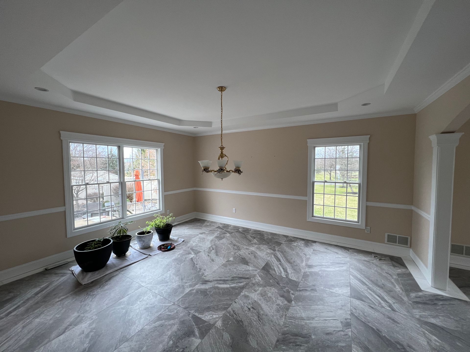 Empty dining room with neutral walls, two windows, and gray herringbone floor.