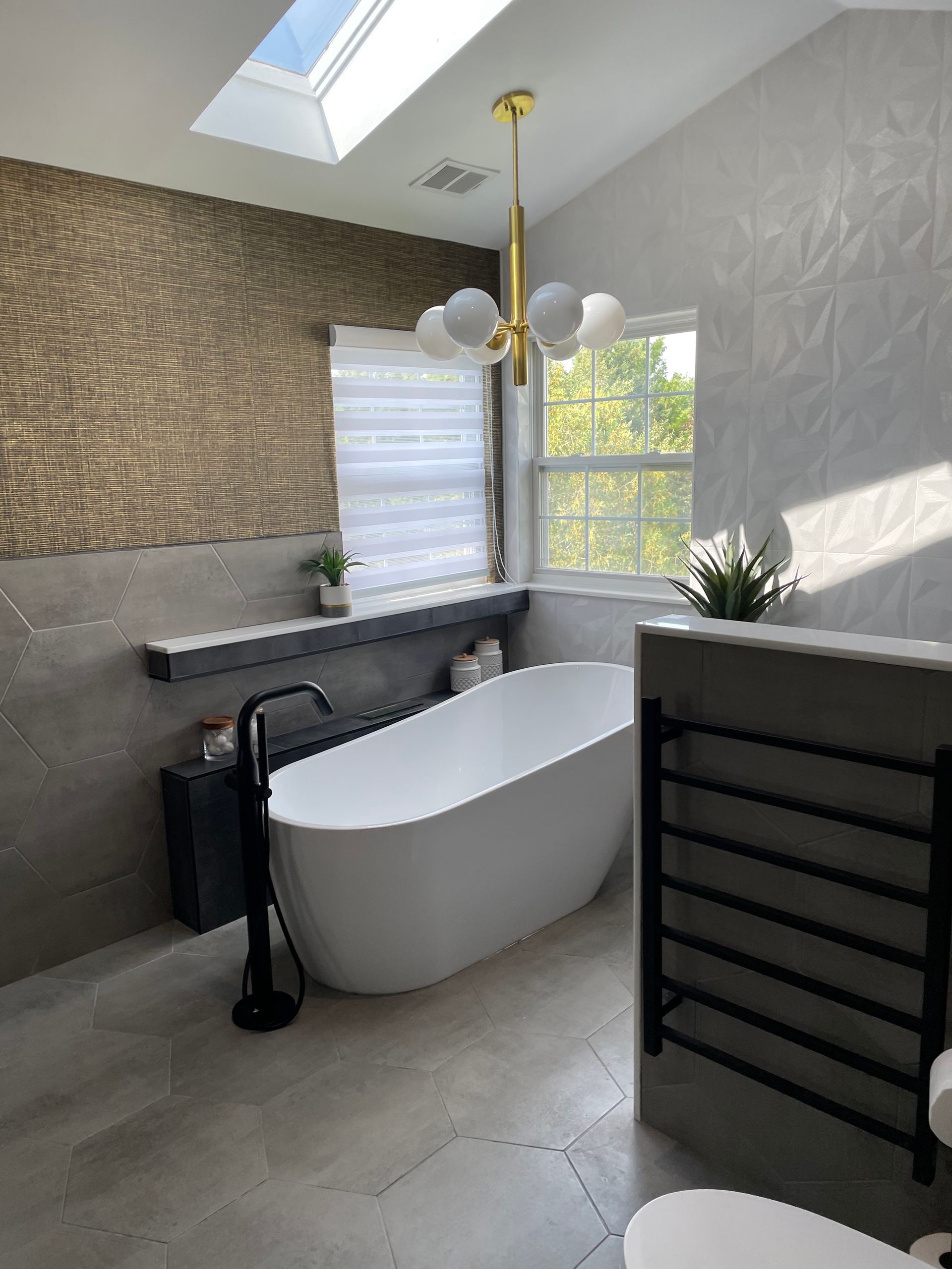 A bathroom with a bathtub , toilet , and skylight.