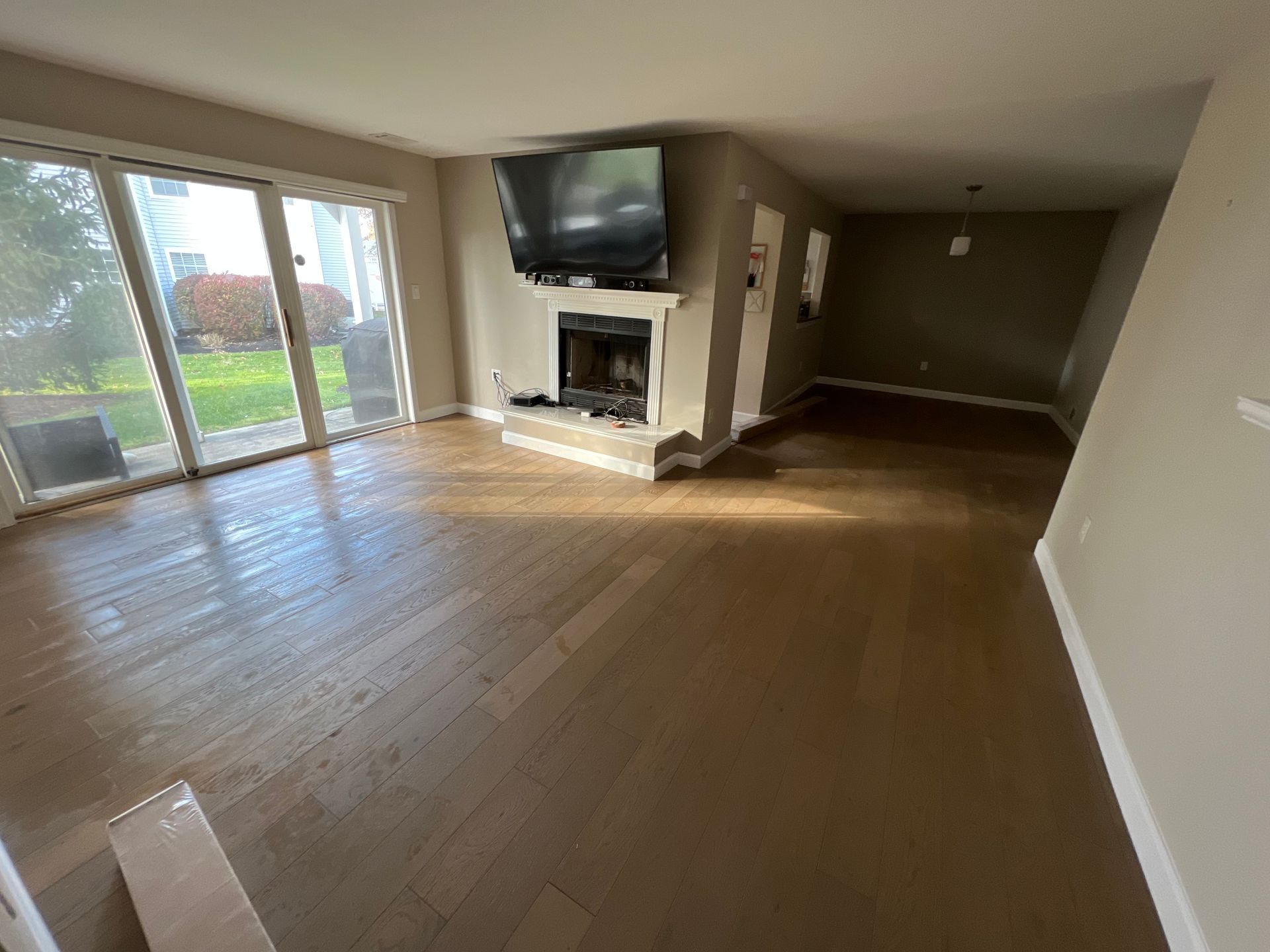 A living room with hardwood floors , a fireplace and a flat screen tv.