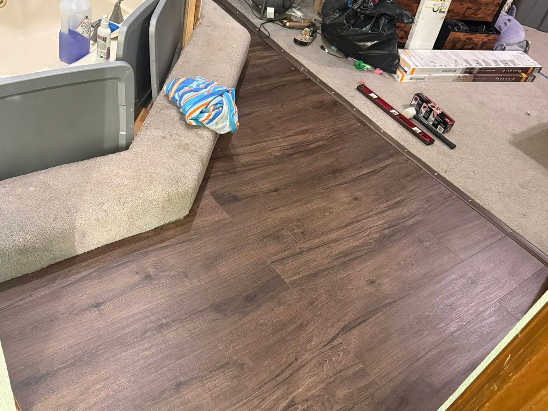 Brown wood-look floor with carpeted seating area and a countertop holding small items and toys