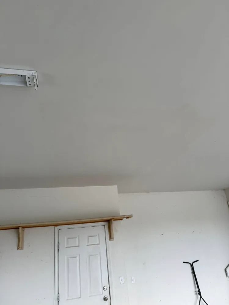 White room with a closed door, wall shelf, and a bicycle partially visible on the right.