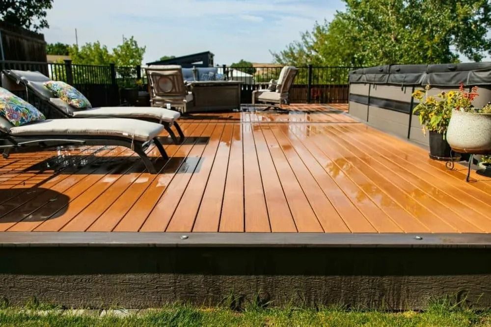 Wooden backyard deck with patio furniture, lounge chairs, and a grill in bright sunlight