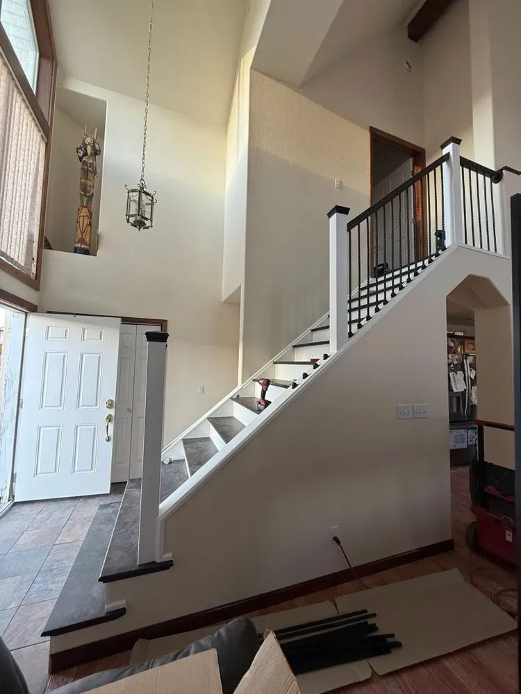 Interior foyer with staircase, white walls, and black railing in a home