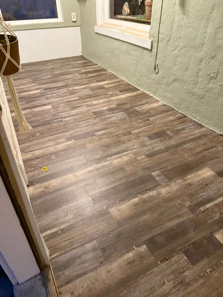Empty room with gray wood-look flooring, green walls, and a window ledge.