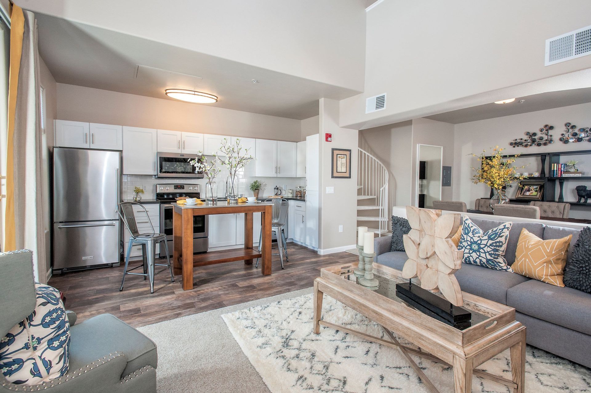 Open-concept kitchen and living area with white cabinets, stainless steel appliances, and a wooden island.