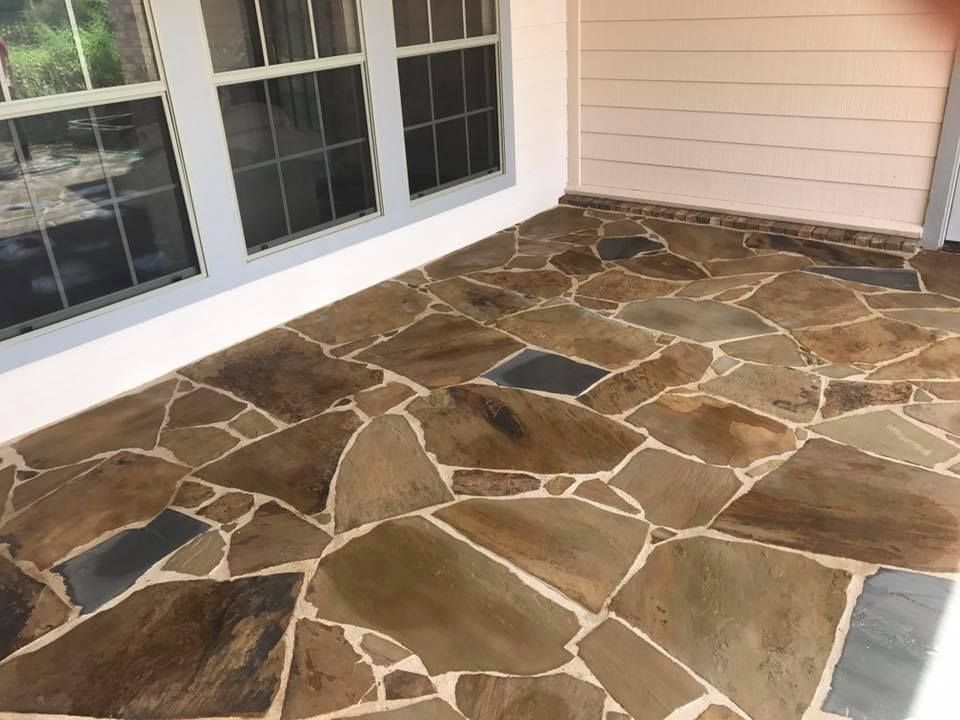 Flagstone patio floor with neutral tones, under windows of a building.