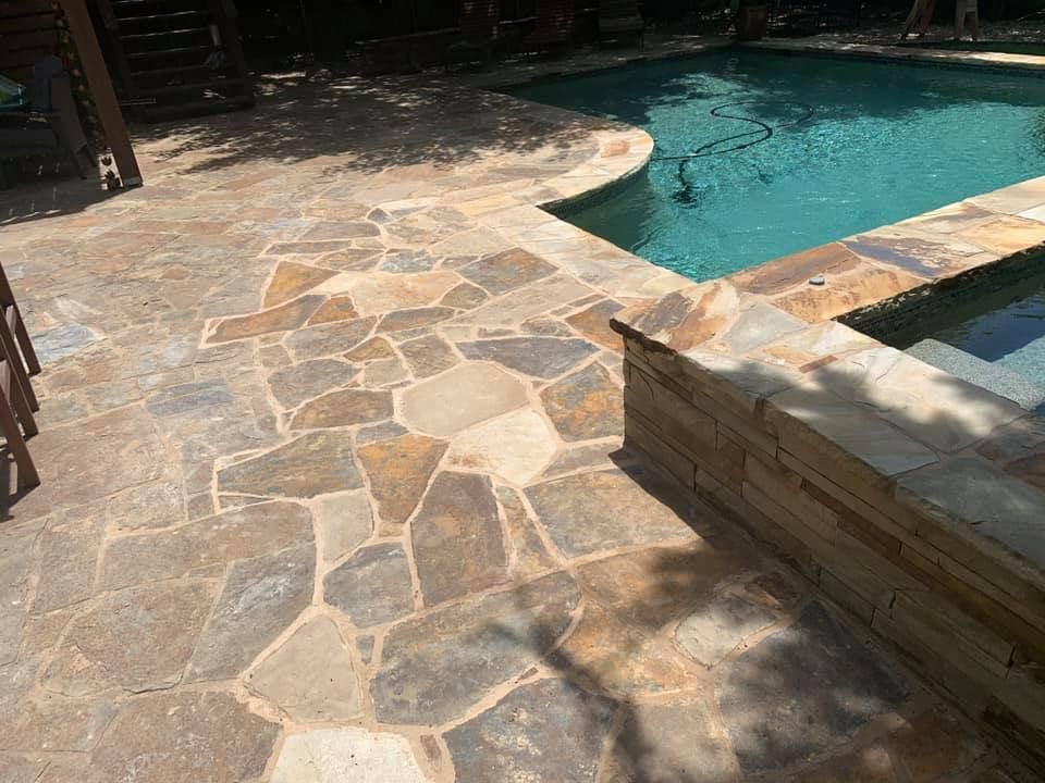 Flagstone patio and pool edge with clear blue water.