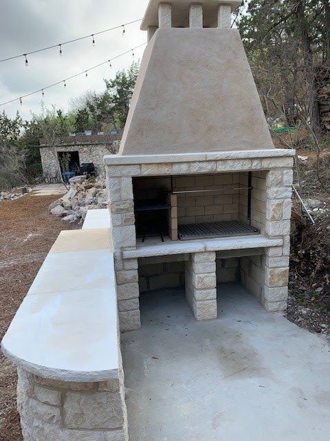 Stone outdoor fireplace with a concrete counter, built on a patio.