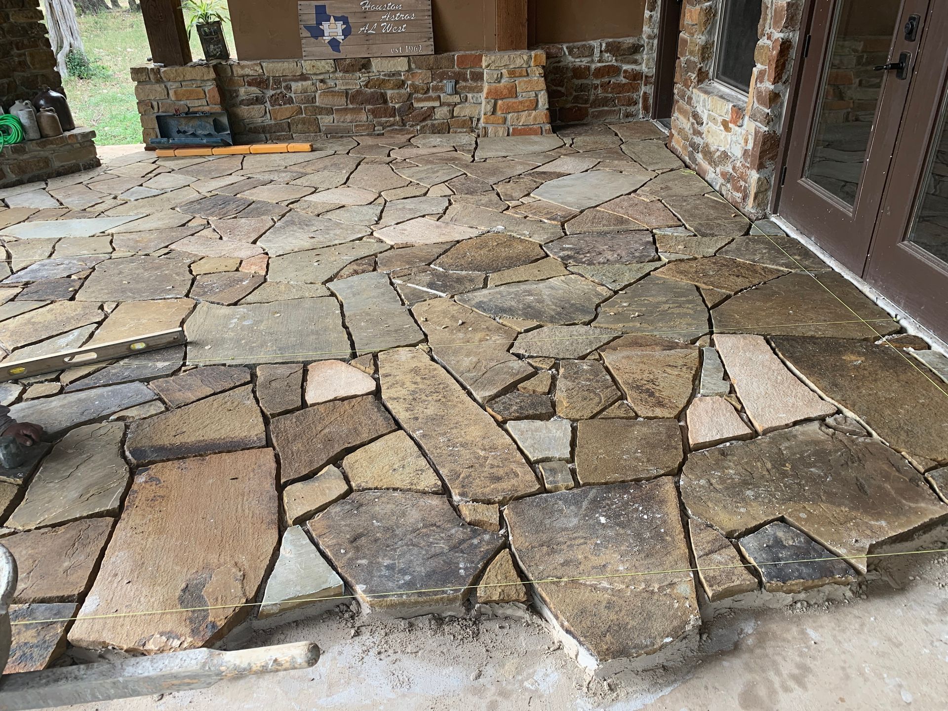 Stone patio being constructed with irregularly shaped, multi-colored flagstones.