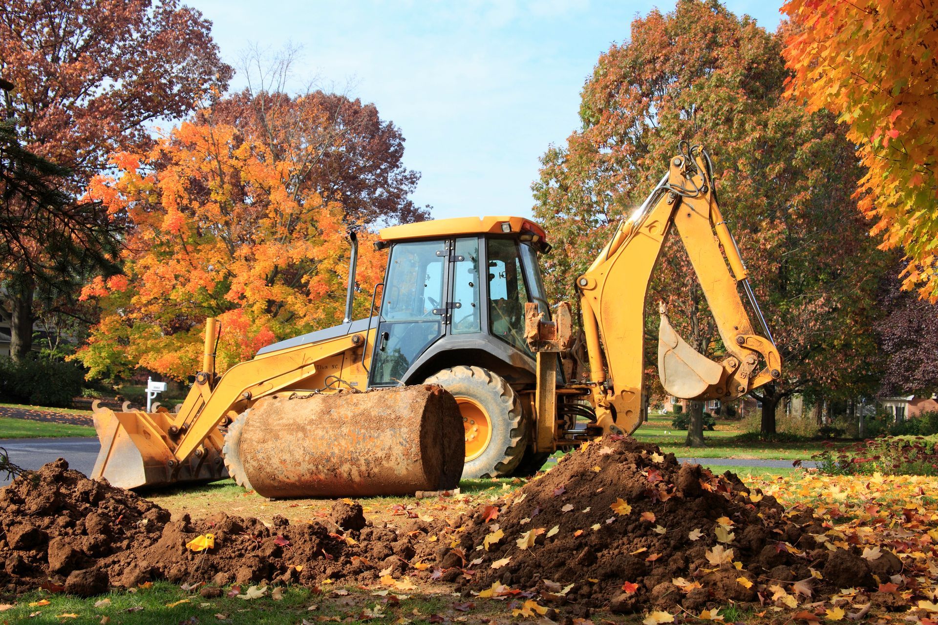 A yellow bulldozer is digging a hole in a yard.