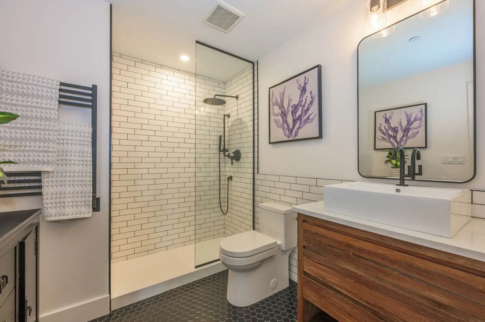 A bathroom with a toilet , sink and walk in shower.
