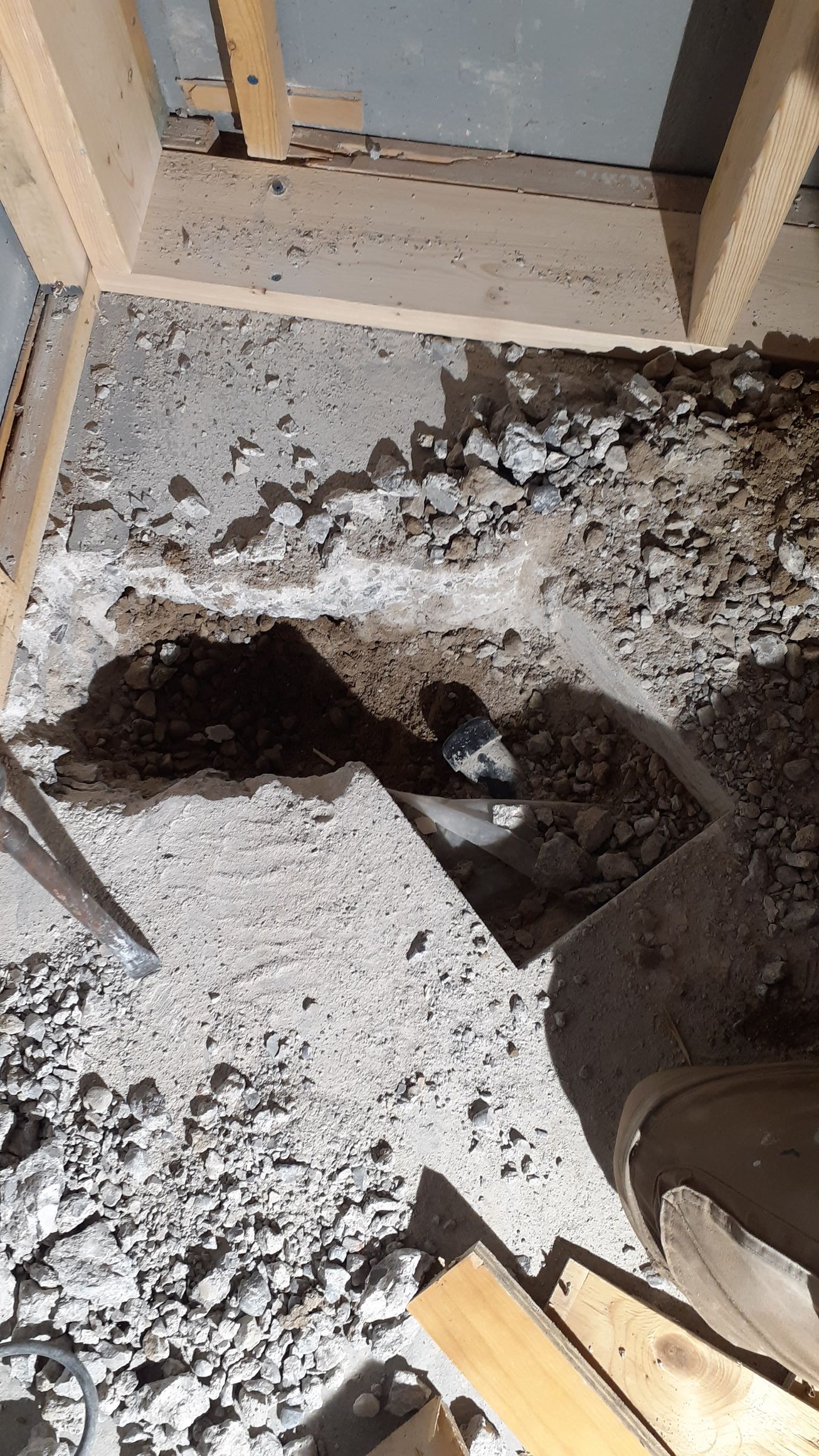 A hole in the floor of a building with a pipe coming out of it.