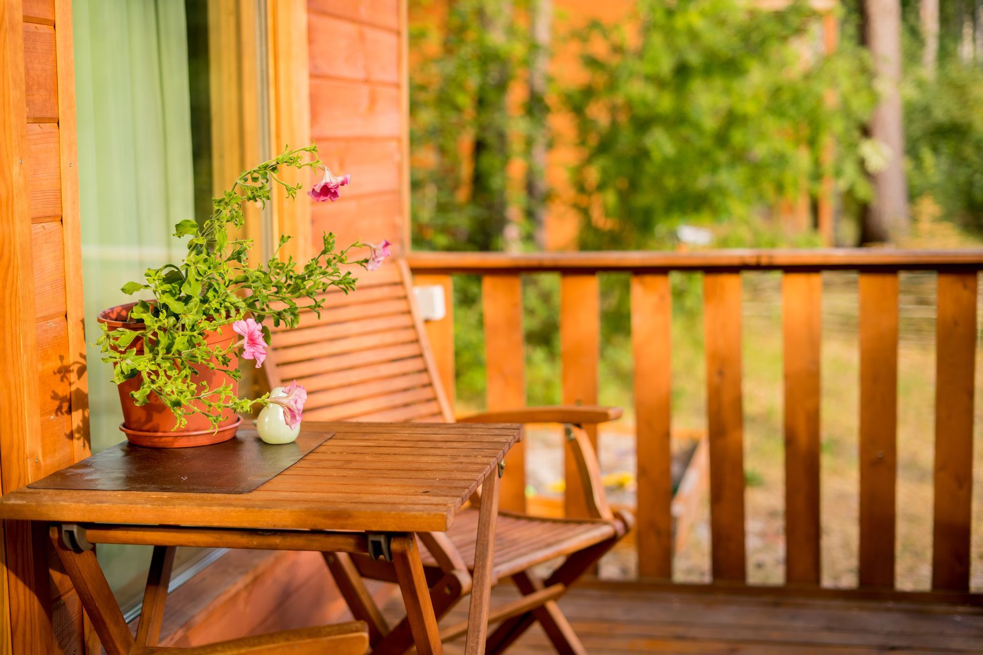 A wooden deck with a table and chairs and a potted plant on it.