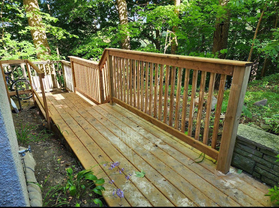 A wooden deck with a railing in the middle of a forest.