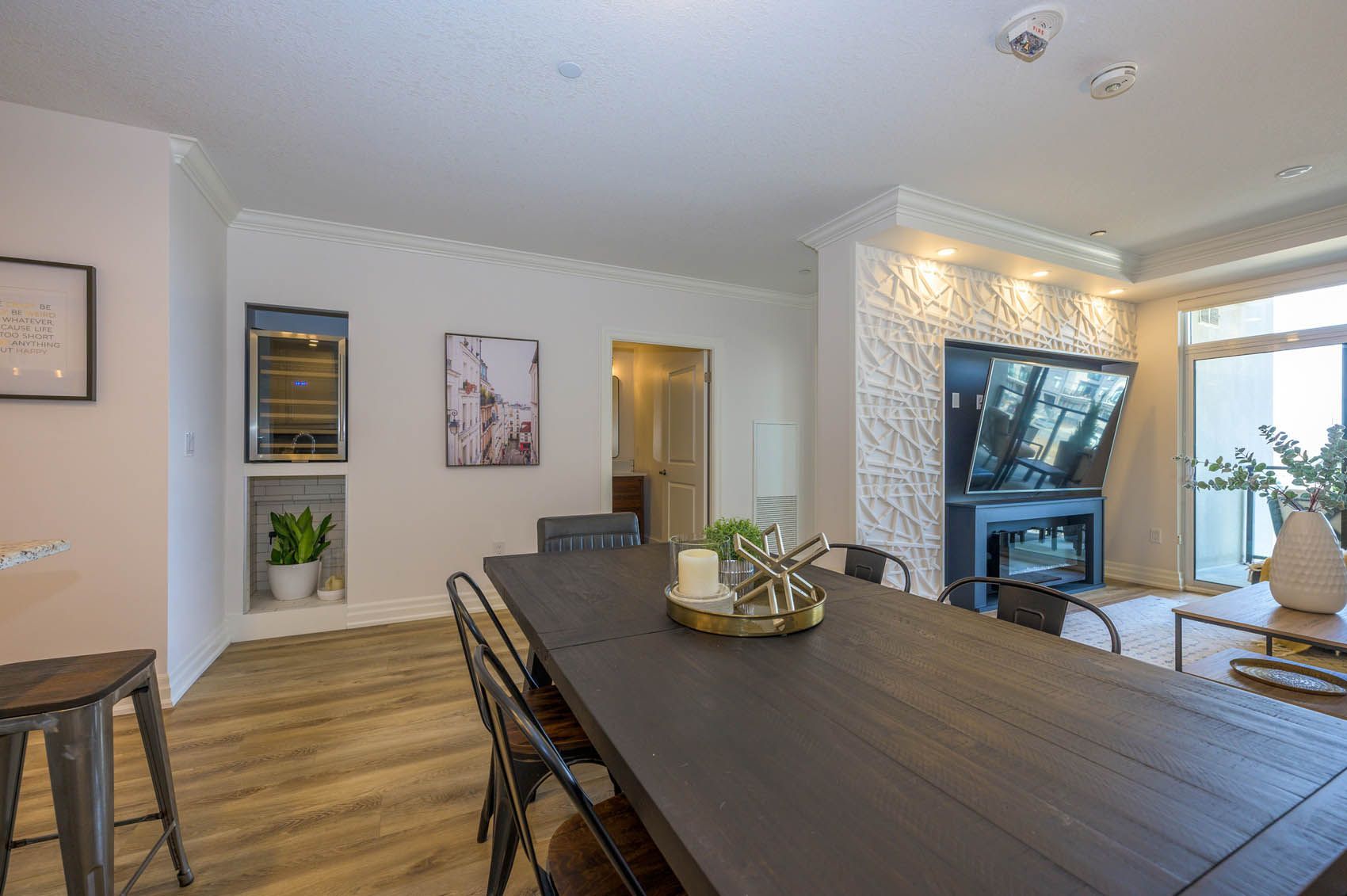 Dining room with dark wooden table, black chairs, fireplace, TV, and decorative wall.